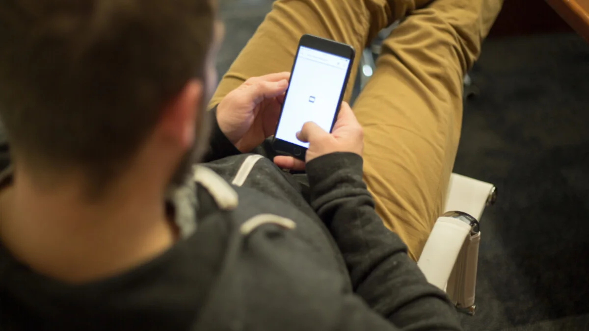 Person hält Smartphone in der Hand und schaut auf den Bildschirm